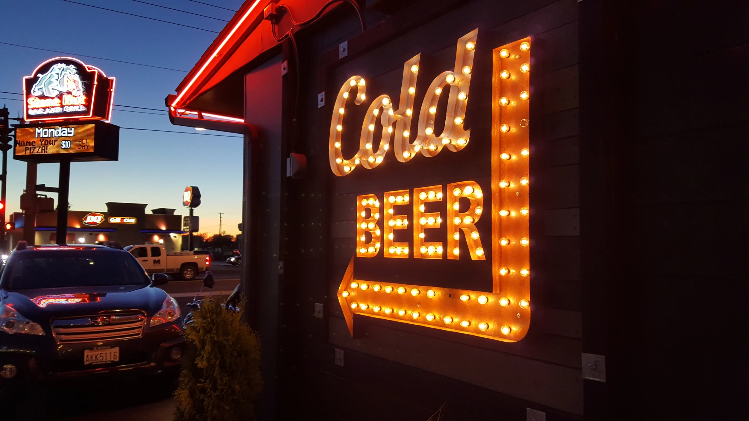 Illuminated Cold Beer wall sign and arrow installed on a business exterior at night