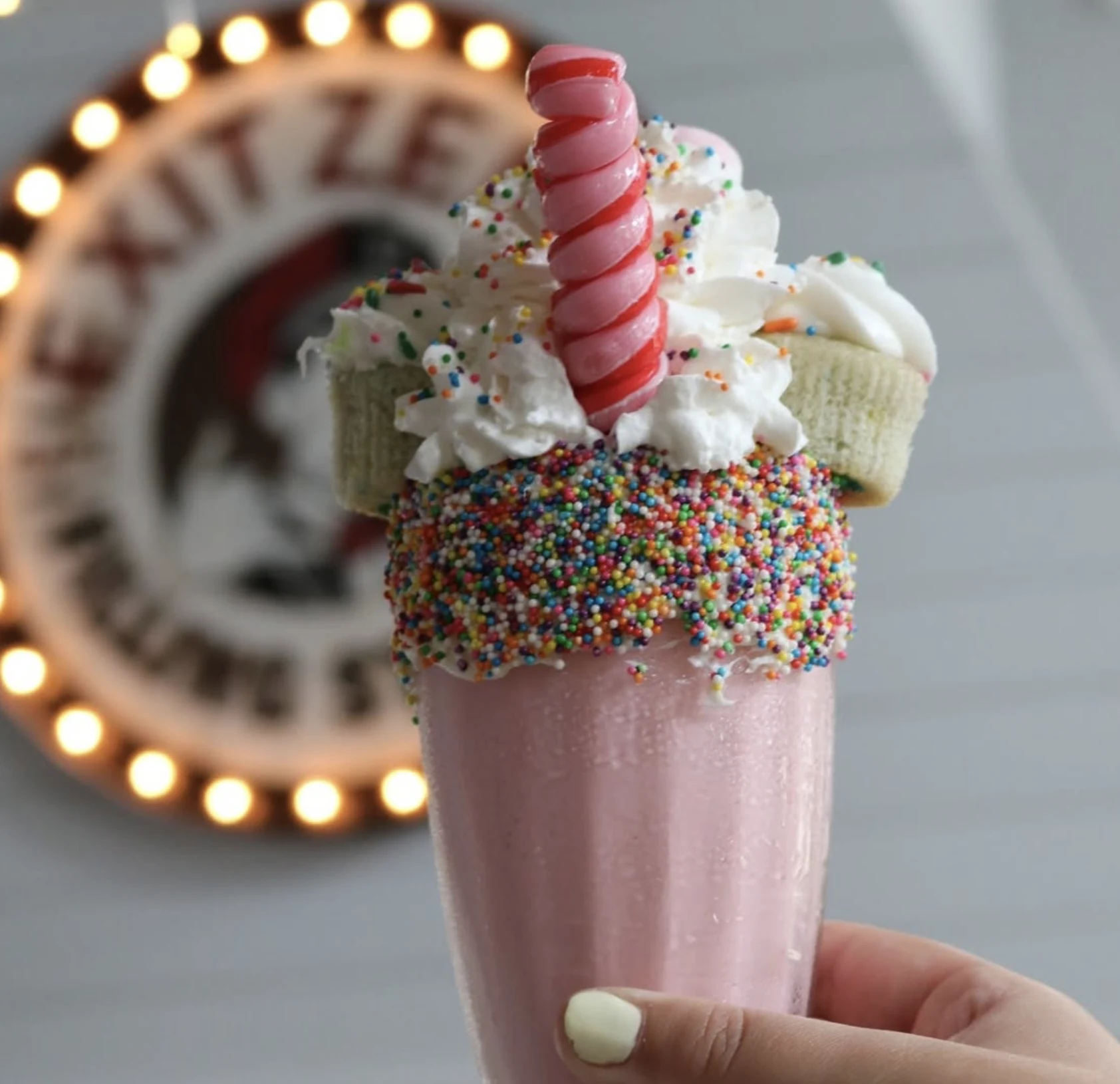 A milkshake with the illuminated Exit Zero sign visible behind it