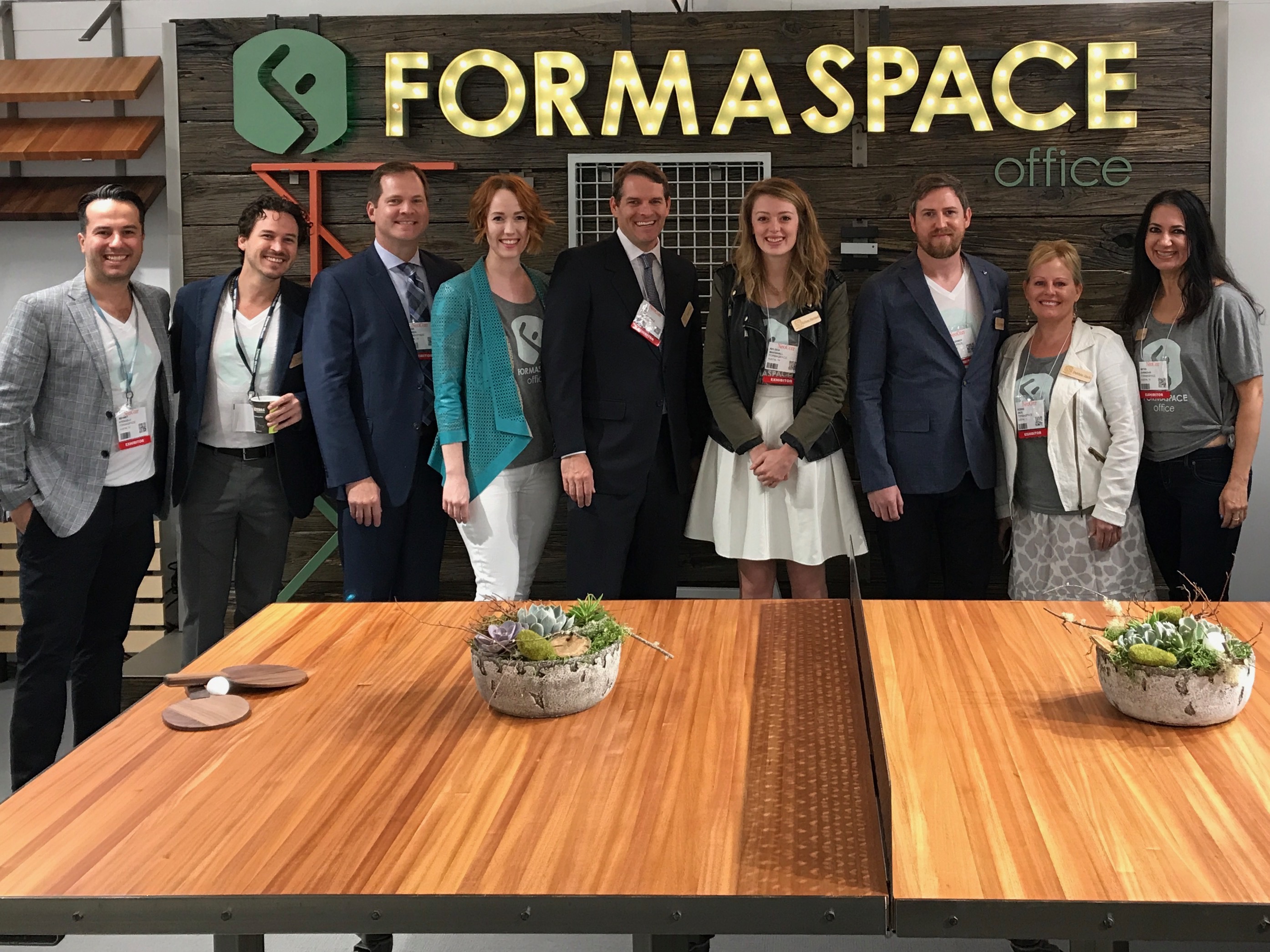 FORMASPACE illuminated office letters above a group at a trade show booth