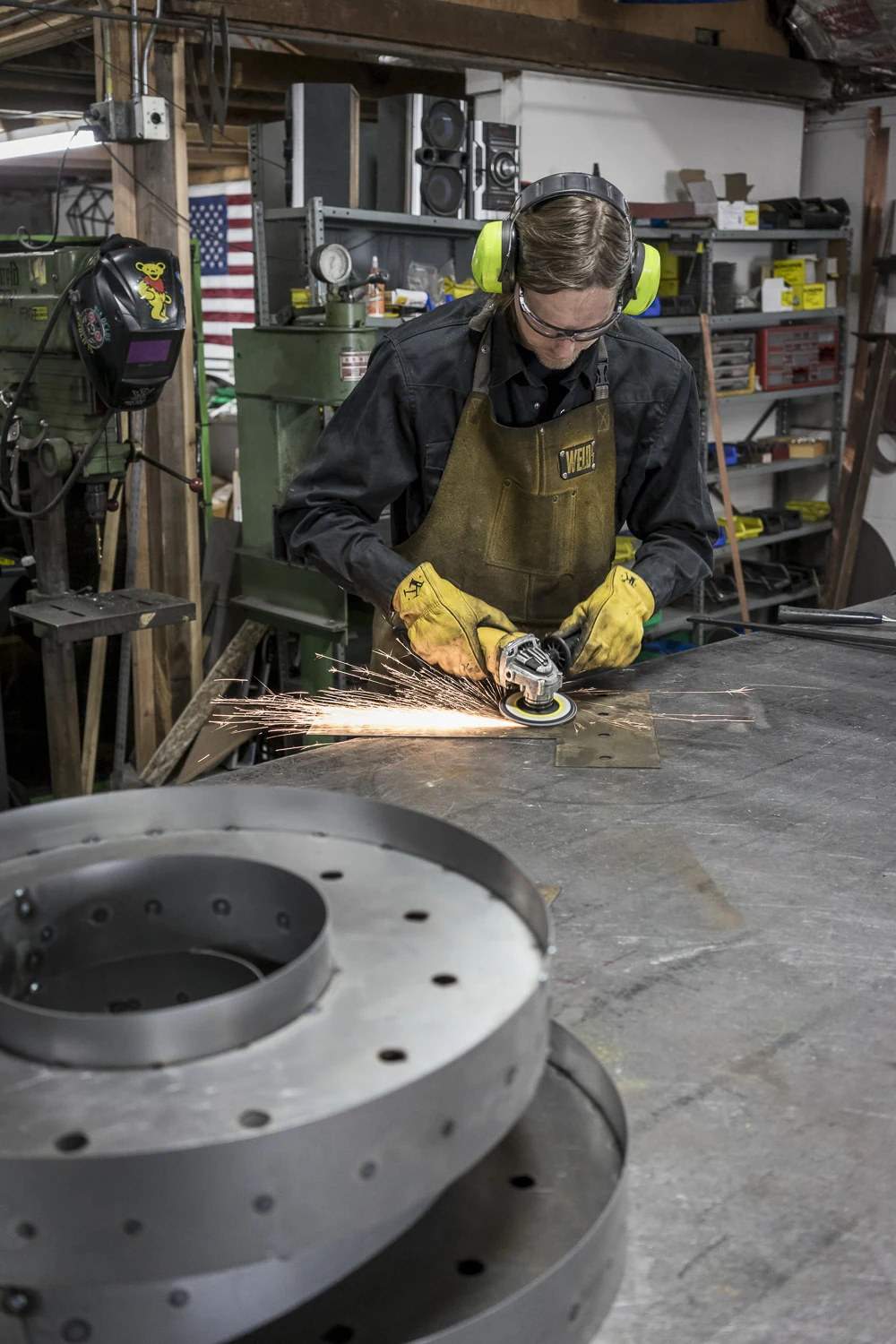 Fabrication crew member grinding a metal piece at a worktable