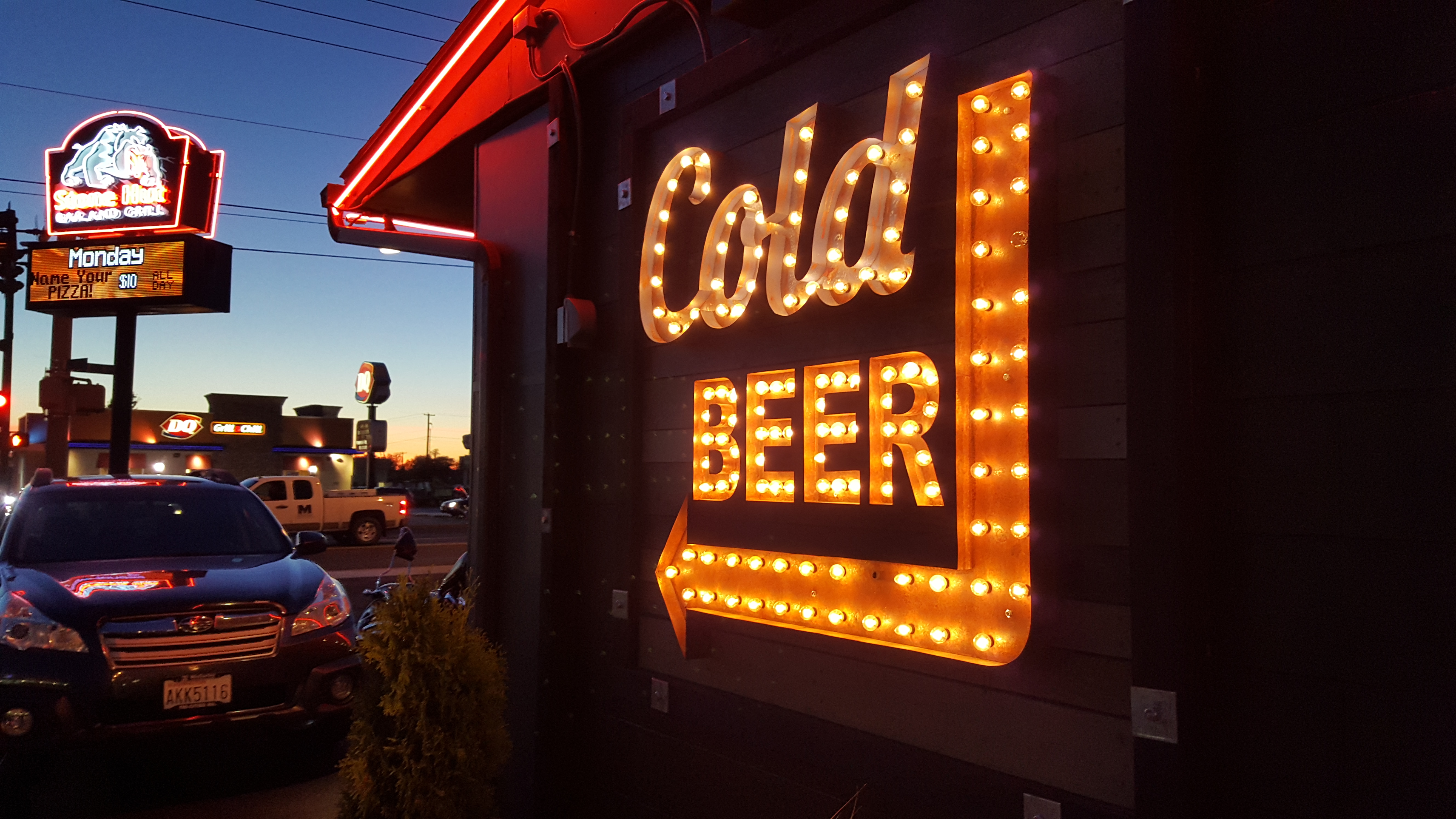 Illuminated Cold Beer arrow sign mounted outside a restaurant at night