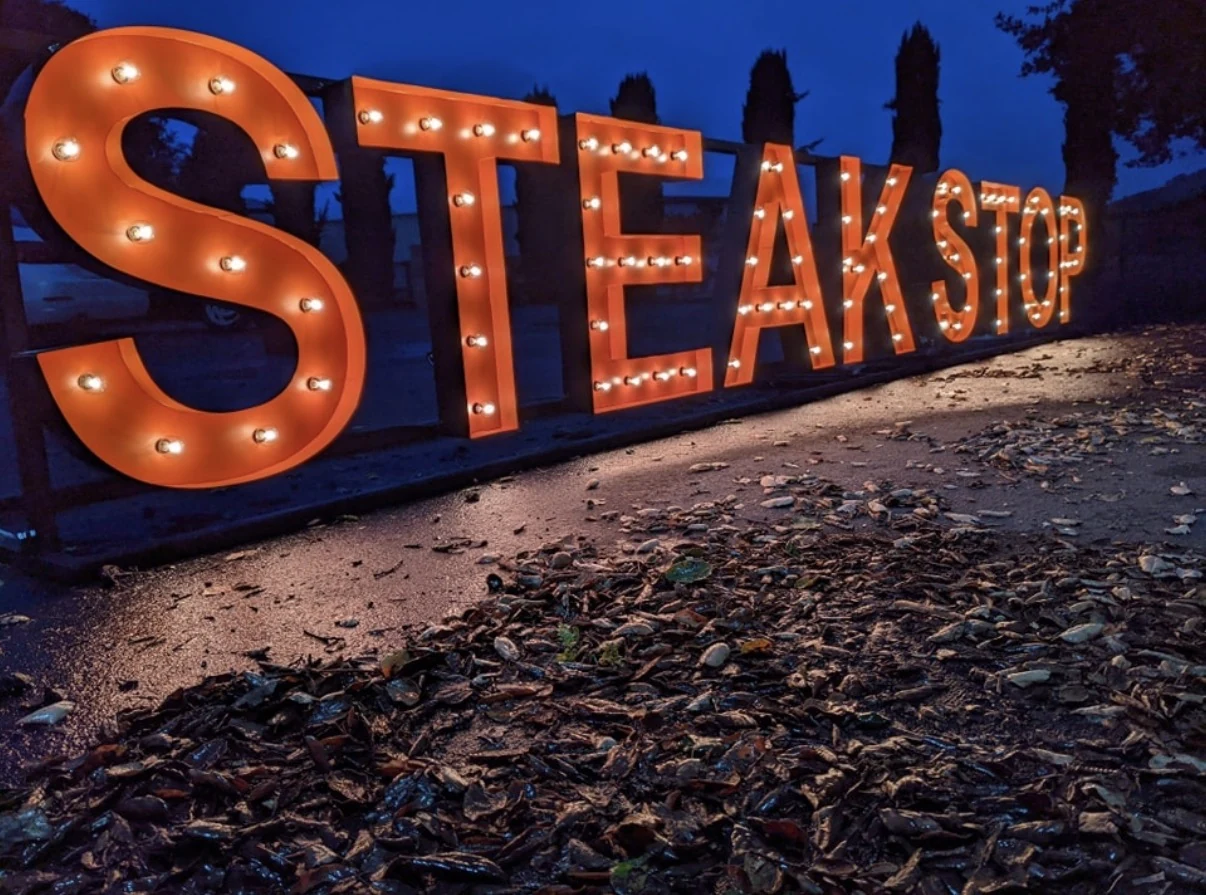 Close angled view of illuminated red STEAKSTOP letters at dusk