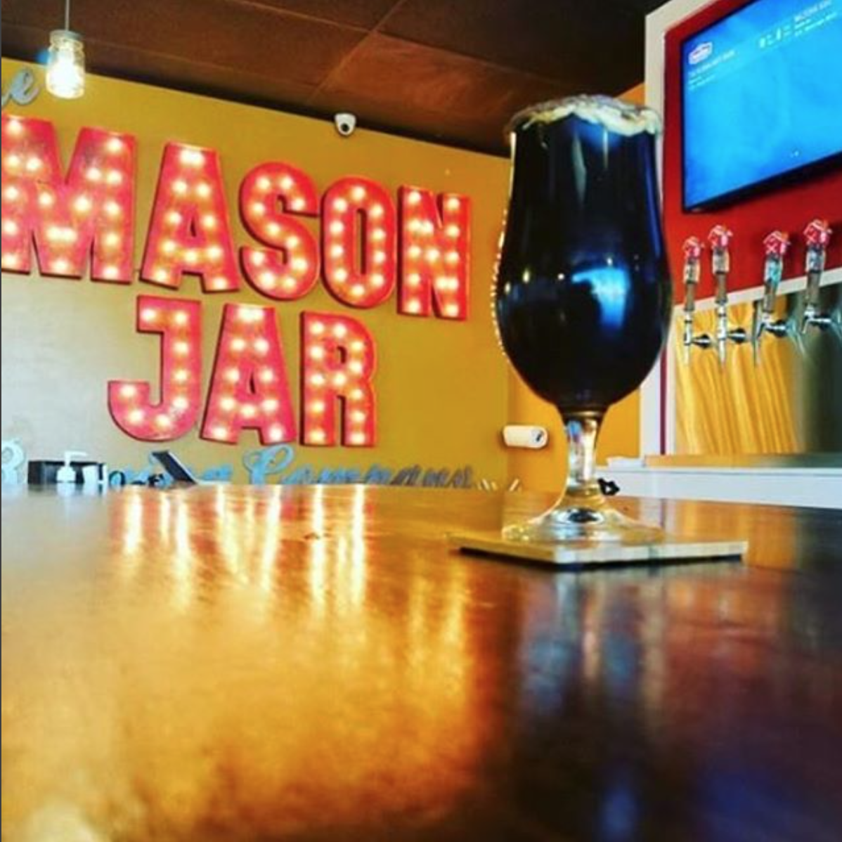 MASON JAR red marquee letters lit behind a restaurant bar