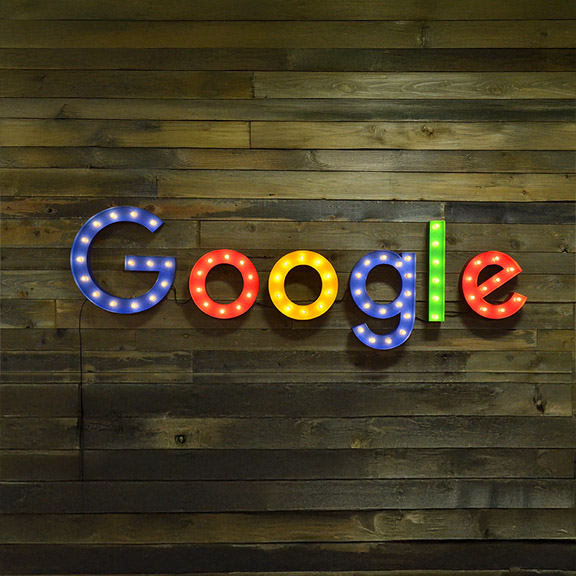 Colorful wall-mounted marquee letters spelling GOOGLE on wood wall