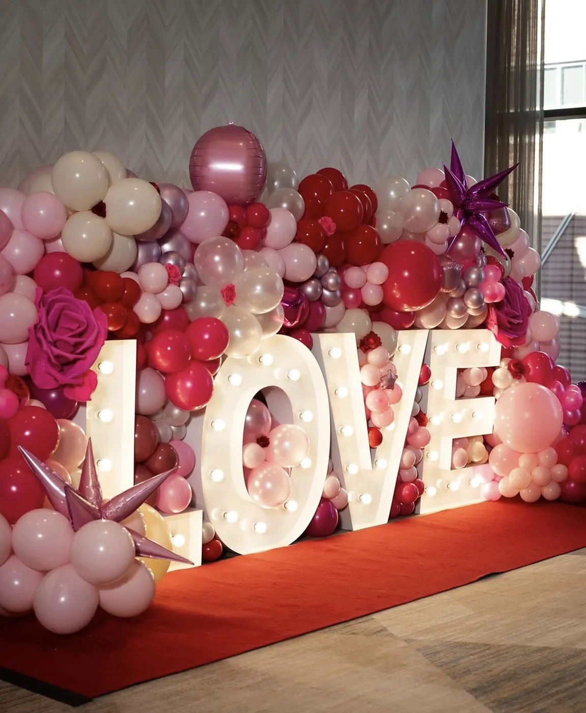 LOVE marquee lights with a red and pink balloon backdrop by C&D Marquees